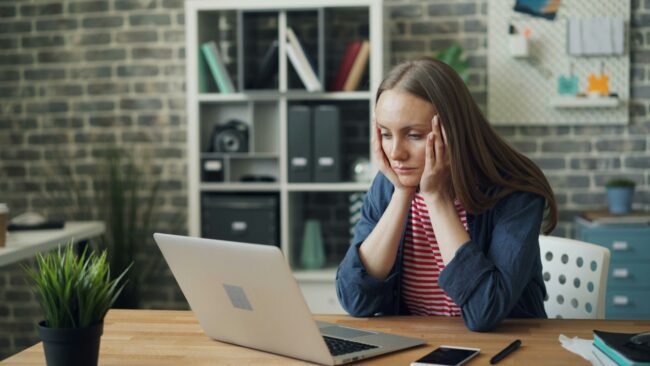 laptop with her head in her hands looking tired